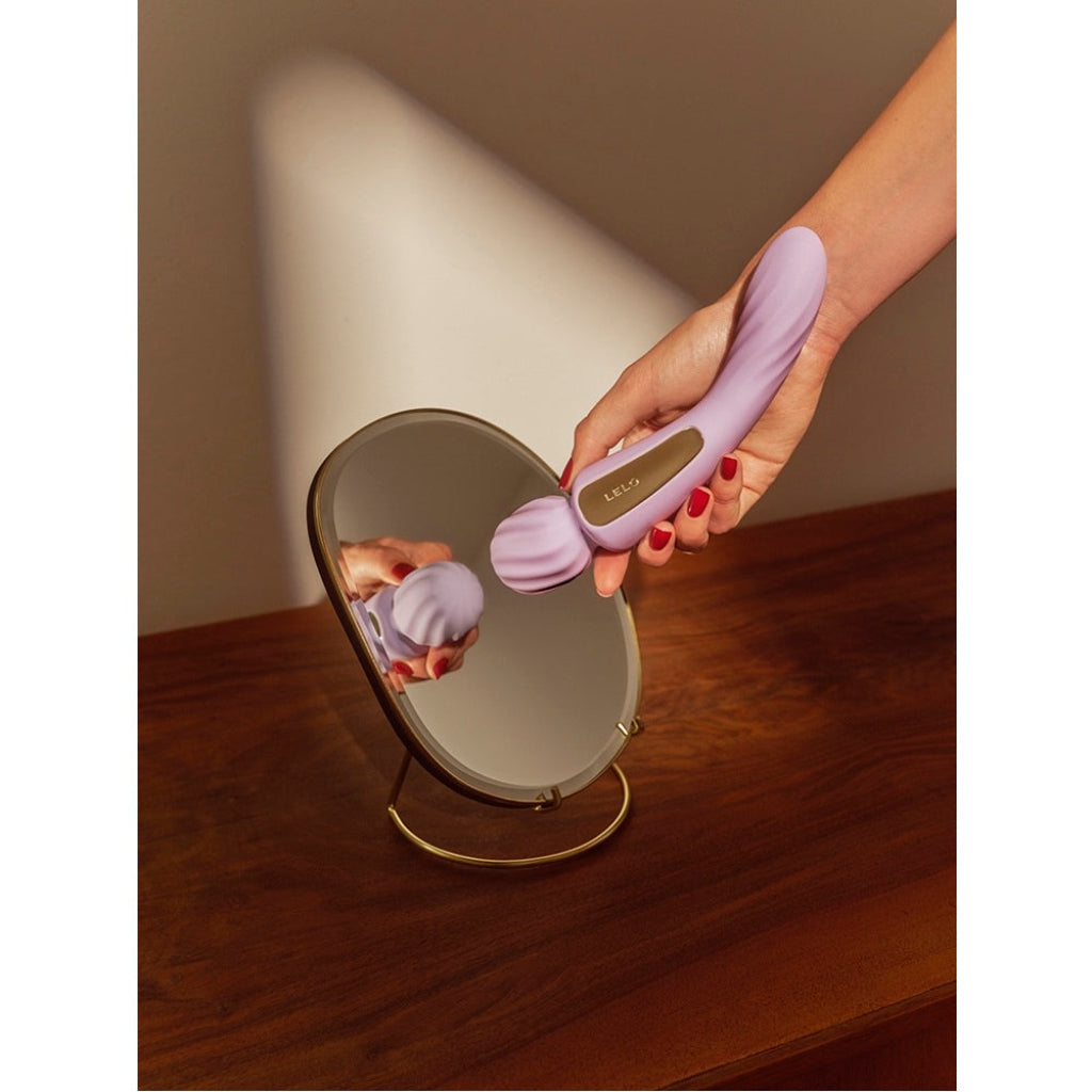 Hand holding a purple wand vibrator with a light on a wooden surface.